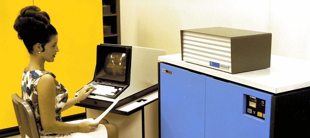 A woman sitting at a 1968 computer terminal.